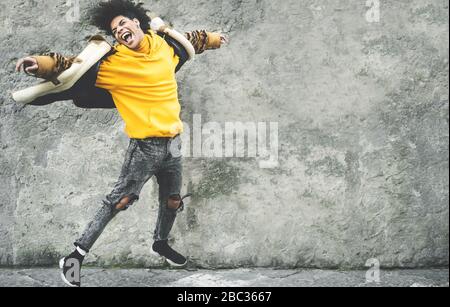 Afro American man having fun dancing in city center - Happy young guy jumping and enjoying positive moments - Millennial generation lifestyle and cool Stock Photo
