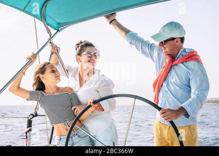 Happy family having fun on sailboat vacation - Mother father and daughter enjoying time together doing luxury boat trip Stock Photo