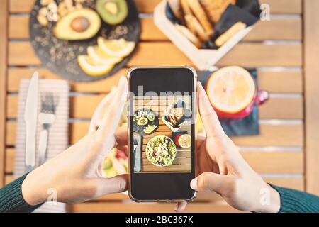 Top view female hands taking photo with mobile smartphone on health lunch food - Young girl having fun with new technology apps for social media Stock Photo
