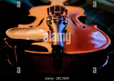 Close up of a violin showing the texture of the wooden body and strings. Soft lighting and shallow depth of field are also used to enhance this image. Stock Photo