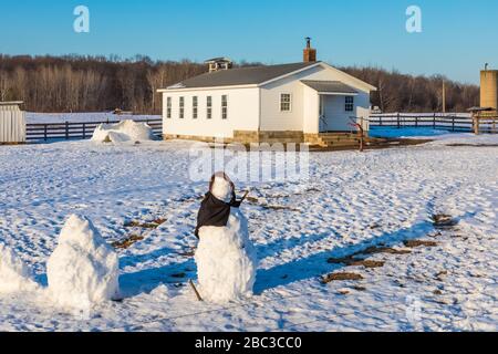 Snowman, really a snow woman, without facial features, made by Amish children at their one-room schoolhouse in central Michigan, USA [No property rele Stock Photo