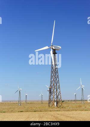 White rotating wind turbine against a clear blue sky. Alternative energy in the Crimea Stock Photo