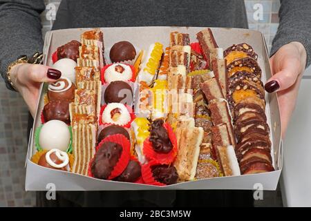 Woman holding large box of cake pieces in her hands Stock Photo