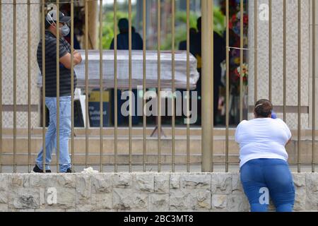 Guayaquil, Ecuador. 02nd Apr, 2020. People wait next to a coffin at the entrance of the cemetery 'Jardines de la Esperanza' (Gardens of Hope). The port city of Guayaquil is the most affected by Covid-19 in Ecuador. Dead bodies lie in the apartments for days, the morgues of the hospitals are overcrowded. The city administration requested four refrigerated containers in which the corpses can be temporarily stored. Credit: Marcos Pin Mendez/dpa/Alamy Live News Stock Photo