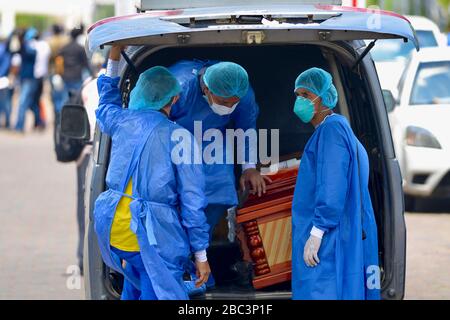 Guayaquil, Ecuador. 02nd Apr, 2020. Men with protective suits load a coffin into a car in front of the hospital General del Guasmo. The port city of Guayaquil is the most affected by Covid-19 in Ecuador. Dead bodies lie in the apartments for days, the morgues of the hospitals are overcrowded. The city administration requested four refrigerated containers in which the corpses can be temporarily stored. Credit: Marcos Pin Mendez/dpa/Alamy Live News Stock Photo