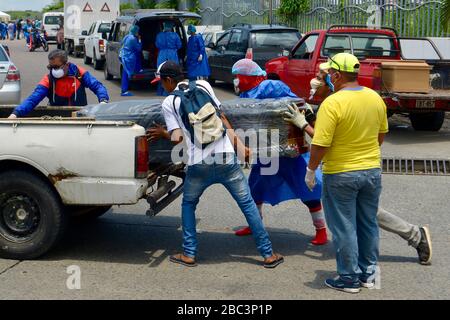 Guayaquil, Ecuador. 02nd Apr, 2020. Men with protective suits load a coffin into a car in front of the hospital General del Guasmo. The port city of Guayaquil is the most affected by Covid-19 in Ecuador. Dead bodies lie in the apartments for days, the morgues of the hospitals are overcrowded. The city administration requested four refrigerated containers in which the corpses can be temporarily stored. Credit: Marcos Pin Mendez/dpa/Alamy Live News Stock Photo