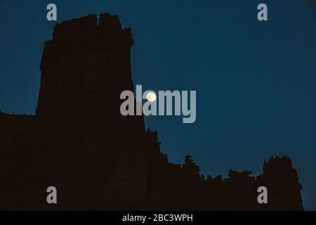 moon rises over the bizarre rock formations of the fisher towers Stock Photo