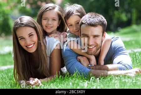 Young Family Lying on the Grass in Park Stock Photo