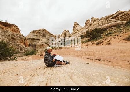 hiker in camo jacket checks his map in a desert arroyo basin Stock Photo