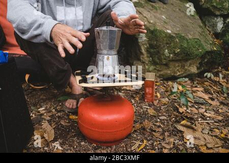 Lower part of a man preparing coffee outdoors Stock Photo
