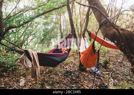 A man and young kid lying in a hammock in the forest Stock Photo