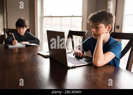 Boys working on their homework on a laptop commuter at home. Stock Photo