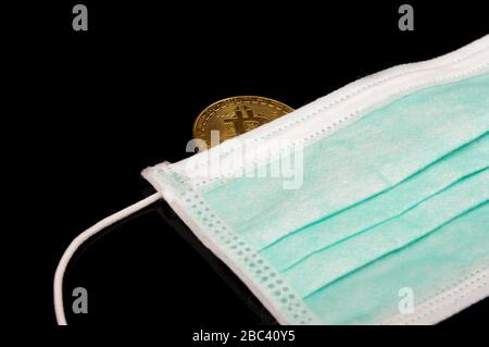 Bitcoin symbolic coin on the face mask isolated on the black background. Corona virus financial crisis concept Stock Photo