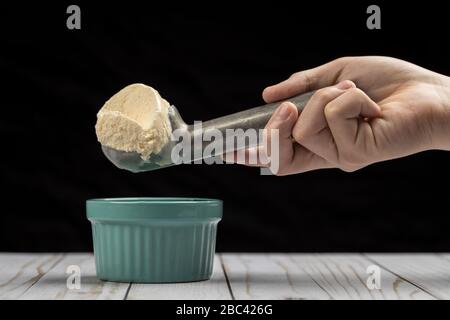 A scoop of vanilla ice cream in a metal ice cream scoop over a bowl. Stock Photo