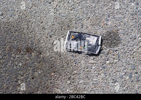 a smashed apart broken cell phone on the pavement of a road Stock Photo