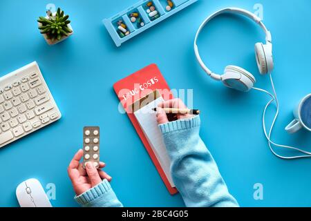 Drug costs calculation. Creative flat lay with pen and calculator in hands. Keyboard, calculator, pills and pill case on mint blue background. Checkin Stock Photo