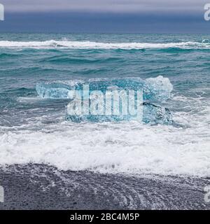 Ice, waves, and cloudy skies by the Jokulsarlon glacial lagoon outlet on southern Iceland Stock Photo