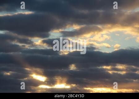 The suns rays pass through the dark clouds. Beautiful dramatic sky at sunset or sunrise. Stock Photo