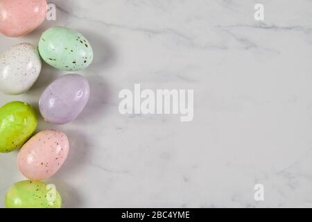 Colorful speckled Easter eggs resting joyously on a white marble background. Stock Photo