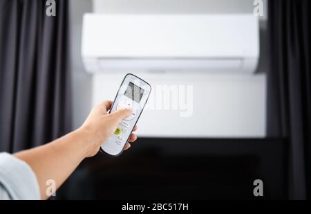 Hand with Remote control on off. Remote Control Directed on the Conditioner Stock Photo