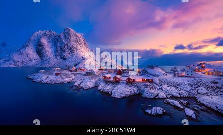 Dawn at the fishing village of Hamnøya, Norway, with snow covered mountain in the background and colorful early morning sky. Stock Photo