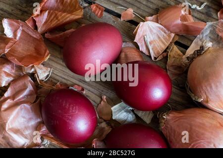 Dyed Easter eggs painted with natural dye onion on rustic wooden background. Process of dyeing eggs with natural paints for Easter. Natural ecological Stock Photo