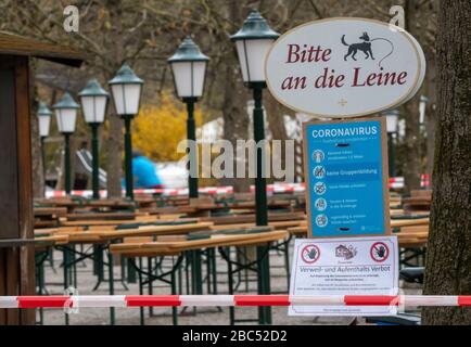 Munich, Germany. 03rd Apr, 2020. Various signs for the containment of the coronavirus hang at the entrance to a closed beer garden in the English garden. Credit: Peter Kneffel/dpa/Alamy Live News Stock Photo