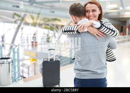 Happy long distance couple hugging after seeing each other at the airport Stock Photo