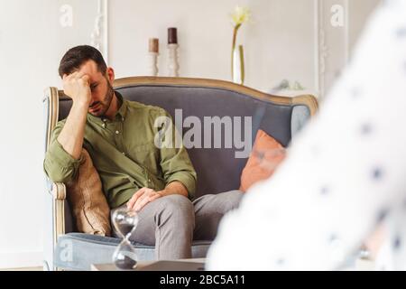 Low-spirited dark-haired male patient on a sofa Stock Photo