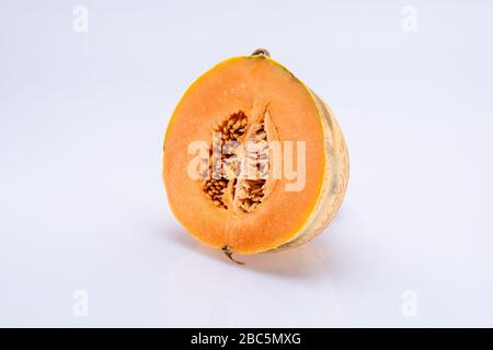 Melon sliced in half with visible seeds inside isolated in front of a white background Stock Photo