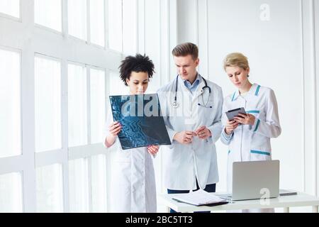 Healthcare, medical: Group of multi-ethnic doctors discussing and looking x-ray in a clinic or hospital Stock Photo