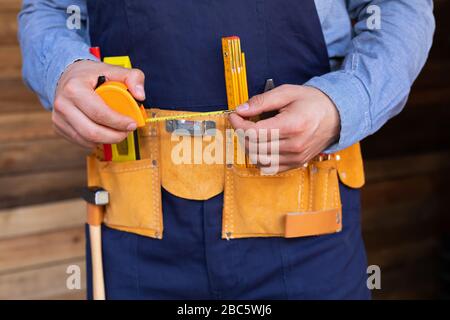 Close up picture of carpenters tool belt and work instruments on wooden background Stock Photo