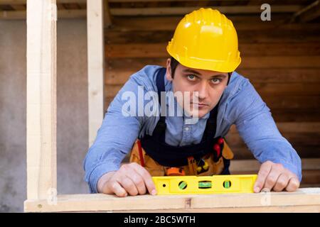 Portrait of a handsome young carpenter measuring lumber with spirit level Stock Photo