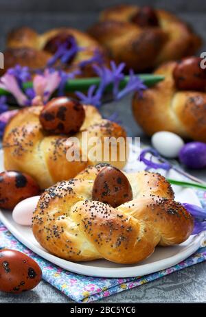 Easter buns, colored eggs and flowers on a gray concrete background. Stock Photo