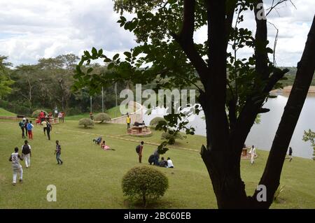 LILONGWE, MALAWI, AFRICA - APRIL 1, 2018: A silhouette of an african tree, behind which teenagers are having party, dancing and rest on the grass near Stock Photo