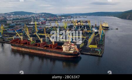 Murmansk, Russia - August 18, 2019: Vessels at the mooring of the coal terminal of the port of Murmansk. Shooting from above drone. Stock Photo