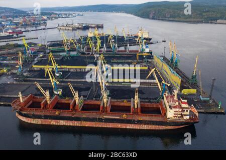 Murmansk, Russia - August 18, 2019: Vessels at the mooring of the coal terminal of the port of Murmansk. Shooting from above drone. Stock Photo
