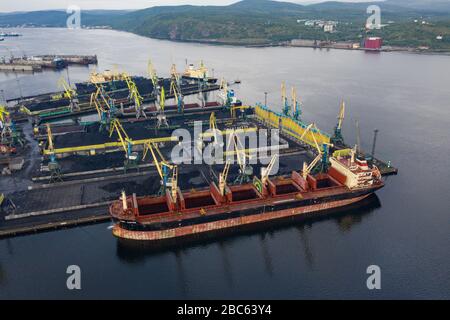 Murmansk, Russia - August 18, 2019: Vessels at the mooring of the coal terminal of the port of Murmansk. Shooting from above drone. Stock Photo
