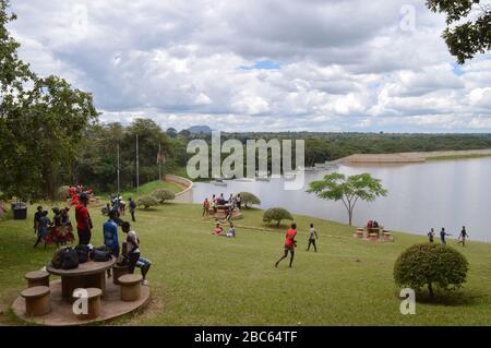 LILONGWE, MALAWI, AFRICA - APRIL 1, 2018: African teenagers are having party, jumping and dancing on the grass. One boy in red t-shirt is running to K Stock Photo