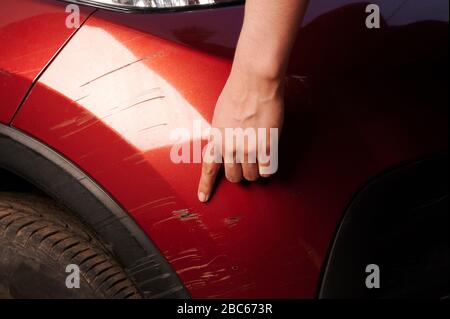 Man point on car scratch in red bumper close up view Stock Photo