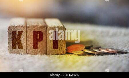 KPI Word Written In Wooden Cubes and coins on burlap canvas. Key Performance Indicator business concept Stock Photo