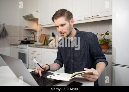 Working from home during Coronavirus outbreak. Happy freelancer man working from home. Portrait of man sitting at his desk in the small apartment kit Stock Photo