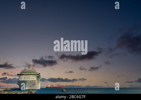 Red Freighter Beyond Cruise Ship at Sundown Stock Photo