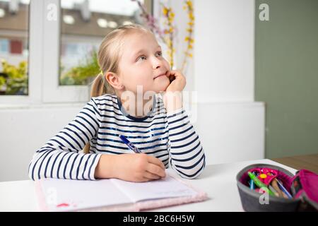 thoughtful student doing homework, pretty girl with blond hair Stock Photo