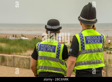 SWANSEA, WALES - JULY 2018: Male and female police officers on patrol on the Swansea seafront.