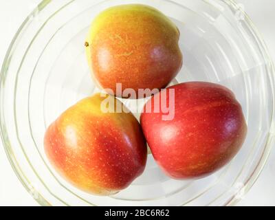 Three braeburn apples in a glass bowl from above on a white tablecloth Stock Photo