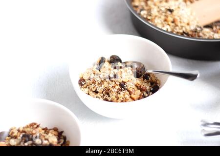 Table Setting of Bowls of Cereals on White Background. Breakfast Bowls of Granola with Nuts and Raisins. Healthy Food Concept. Stock Photo