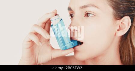 Young woman using inhaler during asthmatic attack at home, closeup, white background Stock Photo