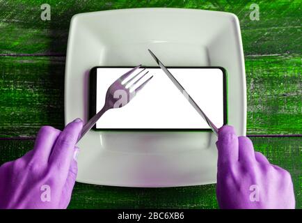Mobile smart phone served as dinner on white plate. Concept of information absorption process, Internet addiction. Dependence on the phone, smartphone Stock Photo