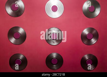 Old vinyl discs hang on a red wall. Stock Photo
